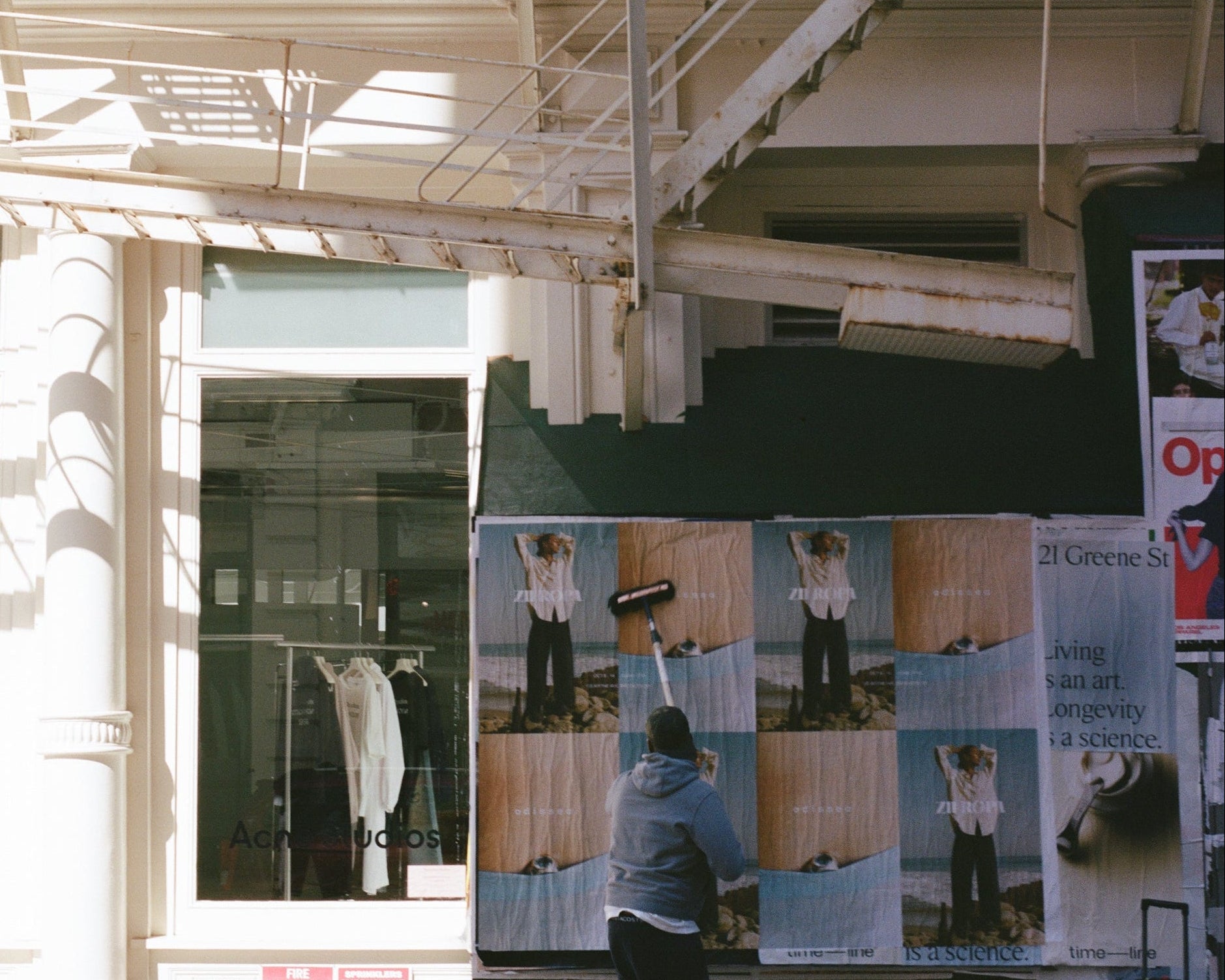 Person walking past a large poster display in an urban setting
