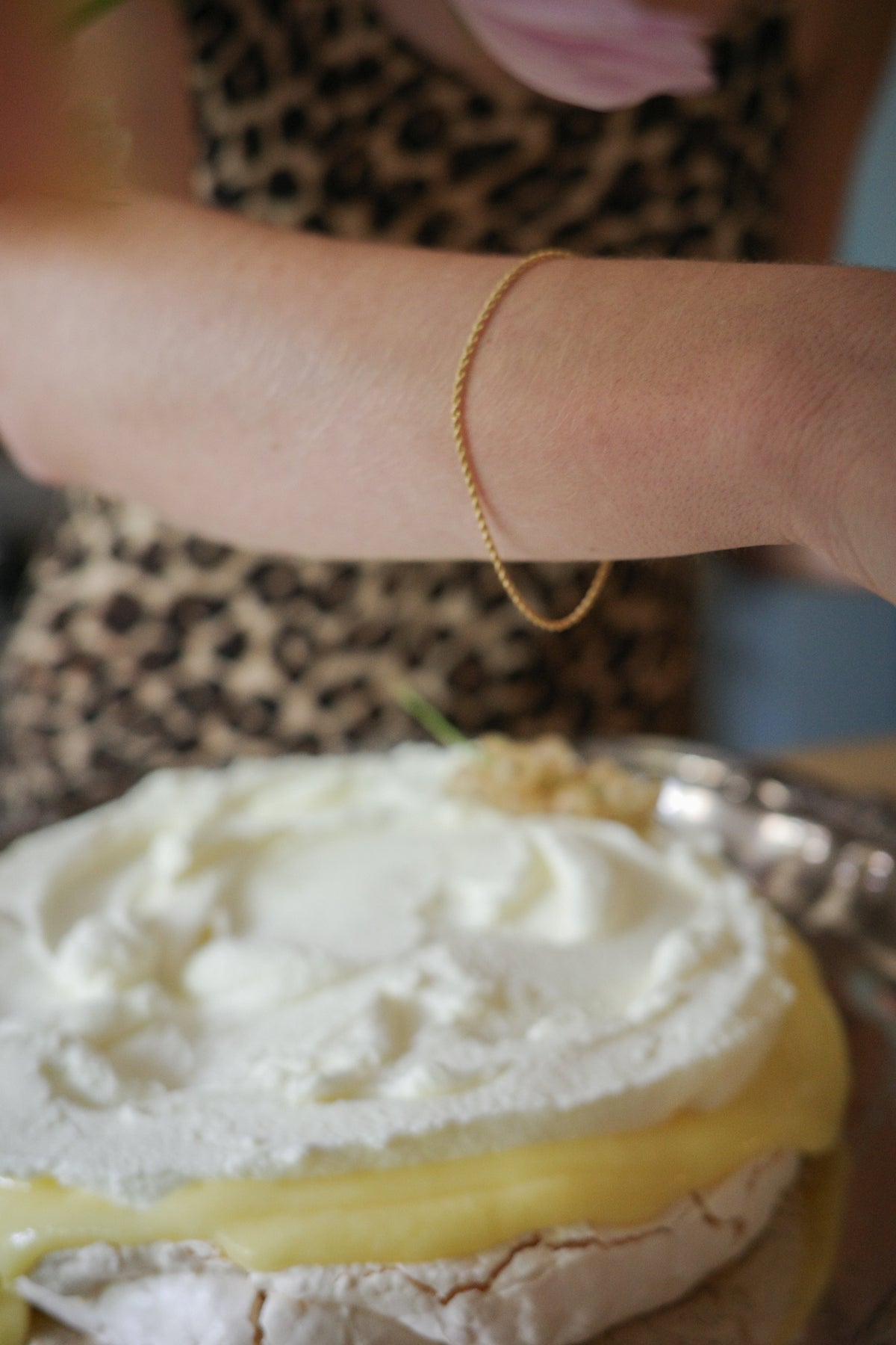 Odissea 14k gold rope chain bracelet worn on a wrist above a cream-topped dessert