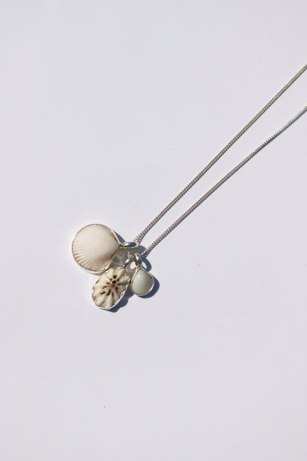 Odissea shell necklace featuring three unique white and patterned shell pendants on a delicate silver chain