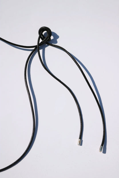 Odissea black leather barrel necklace cord with silver tips and a decorative knot detail on a white background
