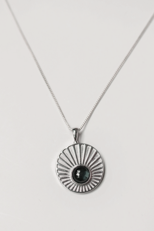 Odissea Helios pendant featuring a blue tourmaline stone set in 14k white gold with sunburst ray detailing on a chain